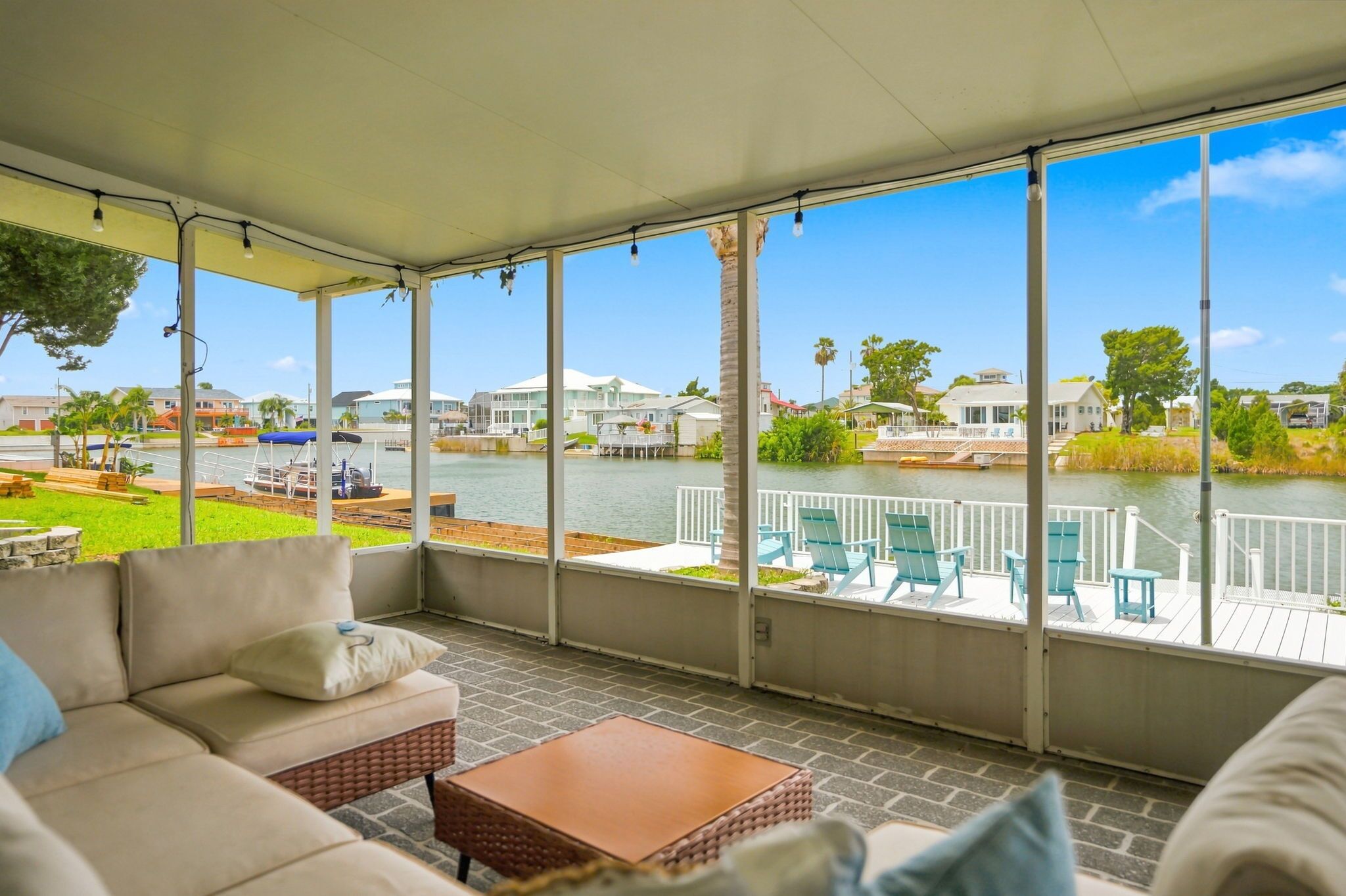 A covered outdoor seating area with a view of a water body and houses in the background.