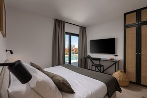 Ein modernes Hotelzimmer mit Bett, Schreibtisch, Fernseher und Blick auf einen Swimmingpool.