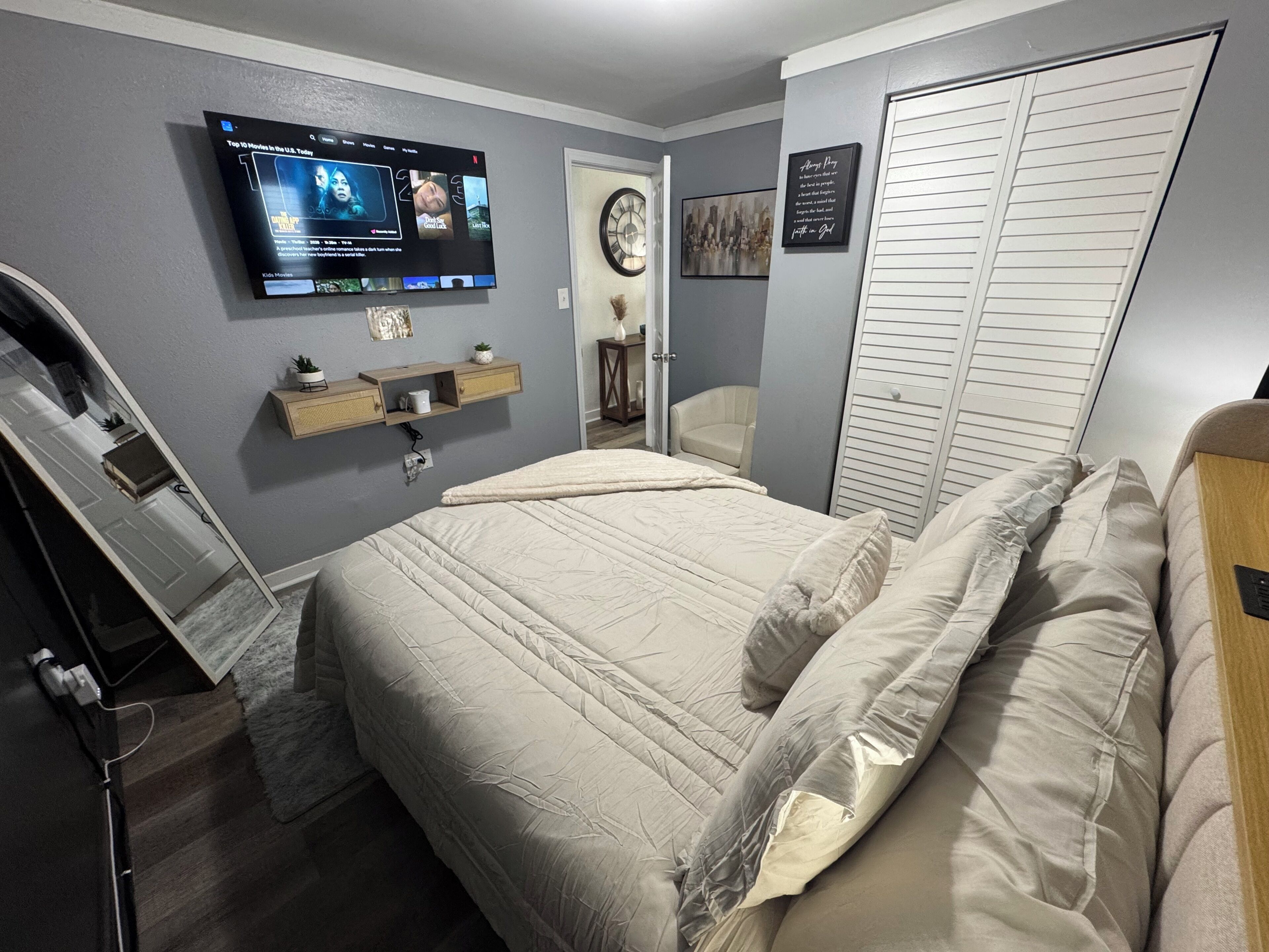 Ein Schlafzimmer mit Bett, Wandfernseher, Nachttisch und Kleiderschrank.