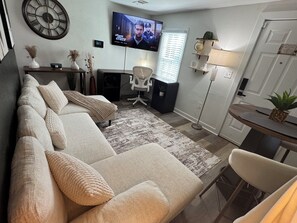 A living room with a sofa, TV, and a small table. - Cozy Midtown Atl Apartment with rivate Backyard (Atlanta)