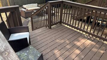 Eine Holzterrasse mit Geländer, Korbmöbeln und einem kleinen Tisch.