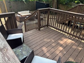 Eine Holzterrasse mit Geländer, Korbmöbeln und einem kleinen Tisch.