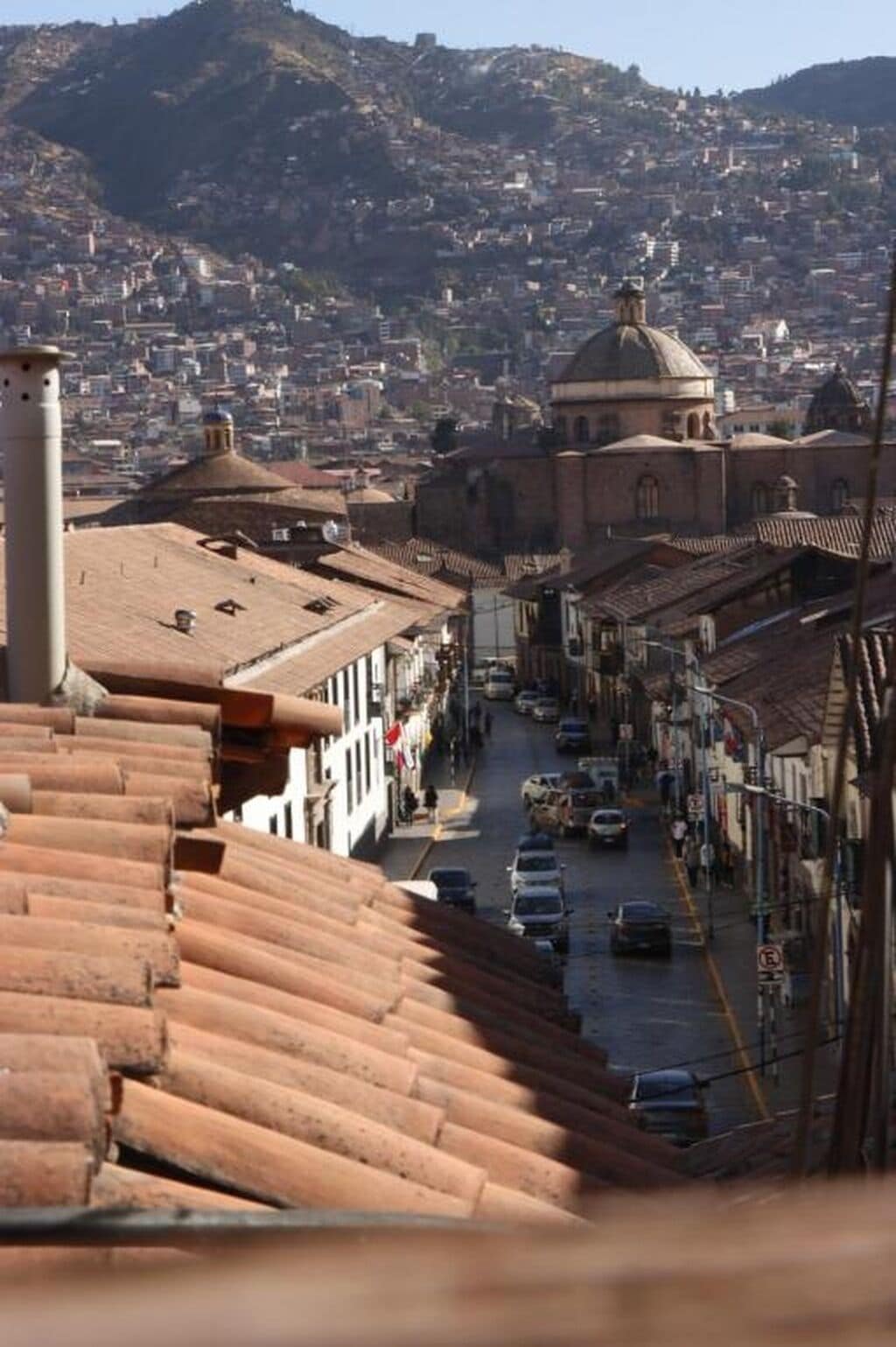 A street view with buildings, a prominent dome structure, and a hilly background.