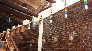 A brick wall with hanging terracotta pots and a wooden staircase. - Casona Terrazas Inn (Cusco)