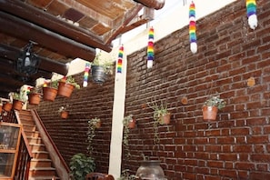 A brick wall with hanging terracotta pots and a wooden staircase. - Casona Terrazas Inn (Cusco)