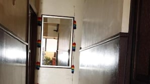 A hallway with wooden flooring, a mirror on the wall, and a door on the right. - Casona Terrazas Inn (Cusco)