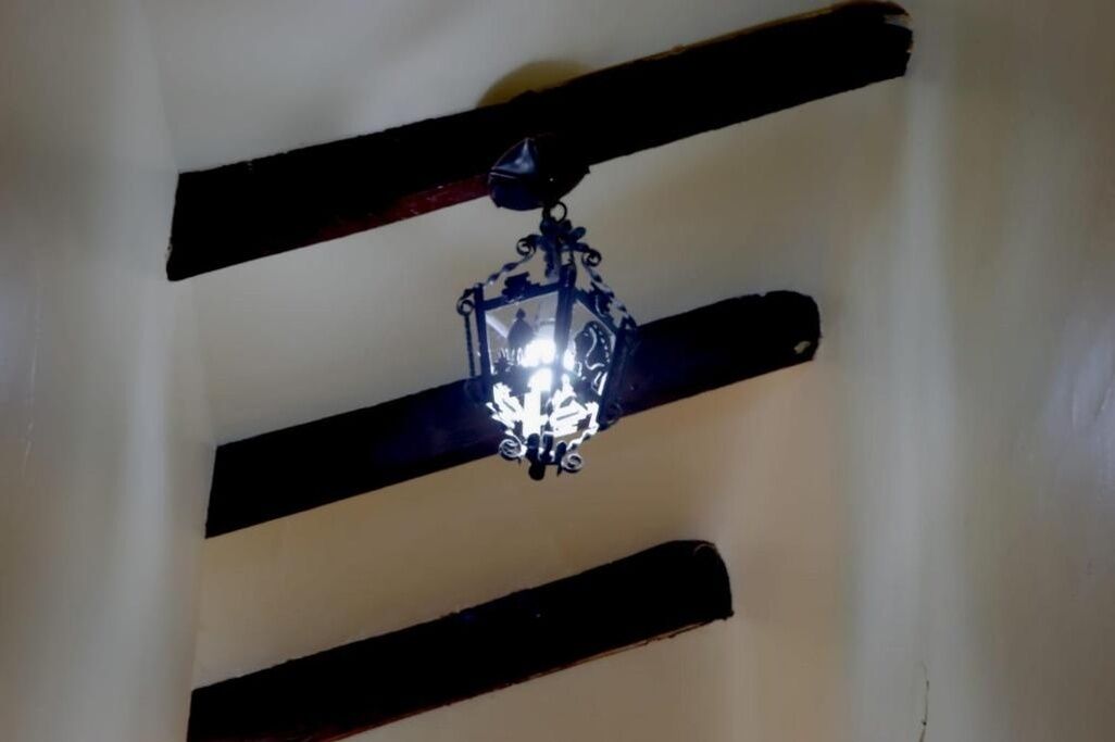 A ceiling with a hanging light fixture and wooden beams.