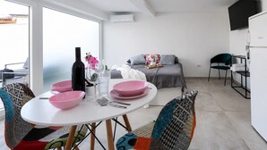 Ein moderner Wohnraum mit Essbereich, einer Couch und einem Fernseher.