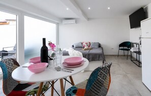 Ein moderner Wohnraum mit Essbereich, einer Couch und einem Fernseher.