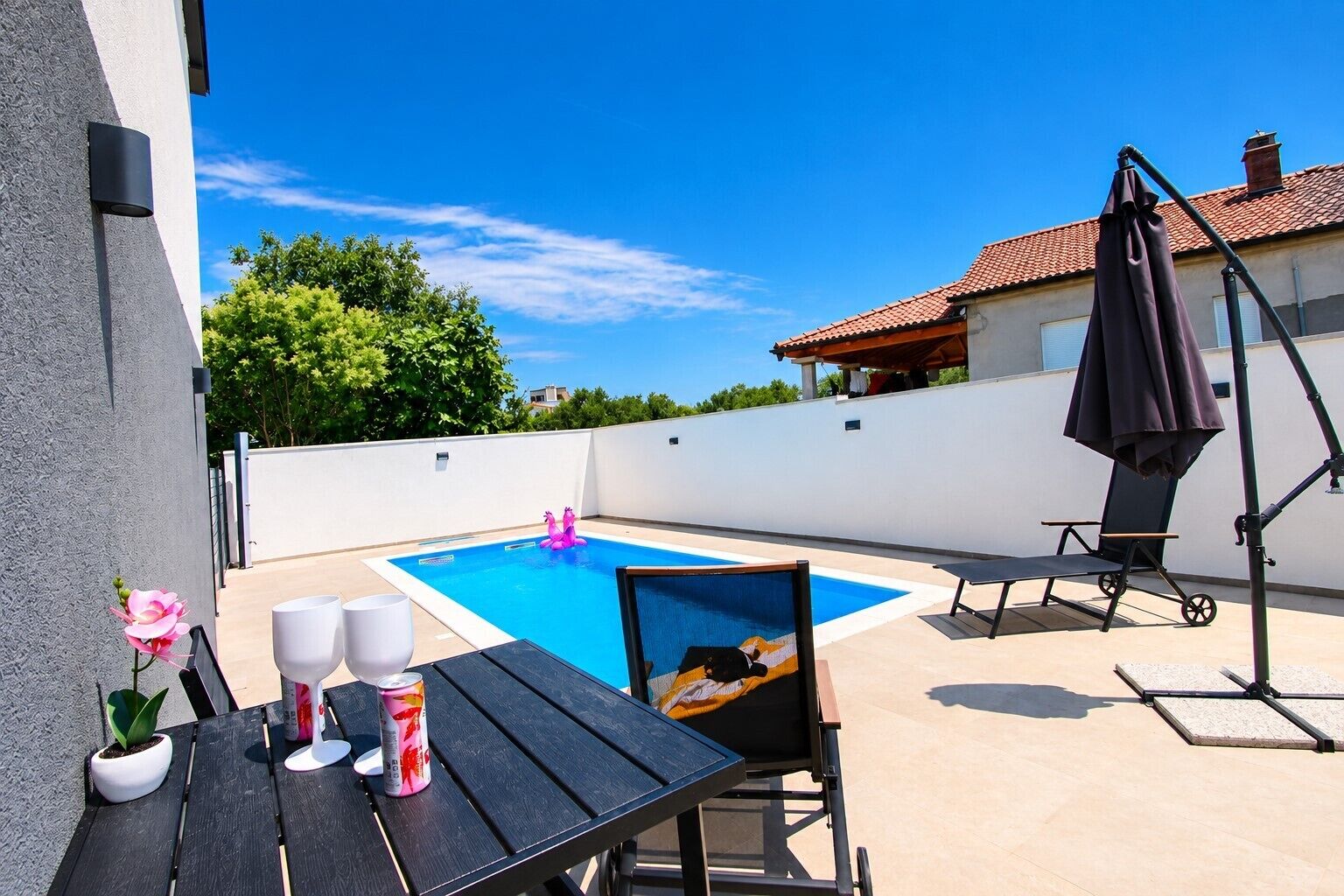 Un jardin avec une piscine, un coin salon extérieur et un parasol.