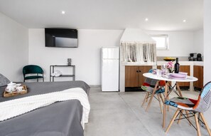 Een moderne hotelkamer met een bed, een televisie, een kitchenette en een eethoek.