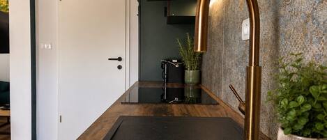 A modern kitchen with a black countertop, a copper faucet, and a potted plant.