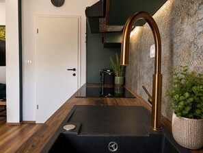 Une cuisine moderne avec un plan de travail noir, un robinet en cuivre et une plante en pot.