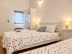 Ein Schlafzimmer mit Bett, Nachttischen, einem Kleiderschrank und einem Fenster.