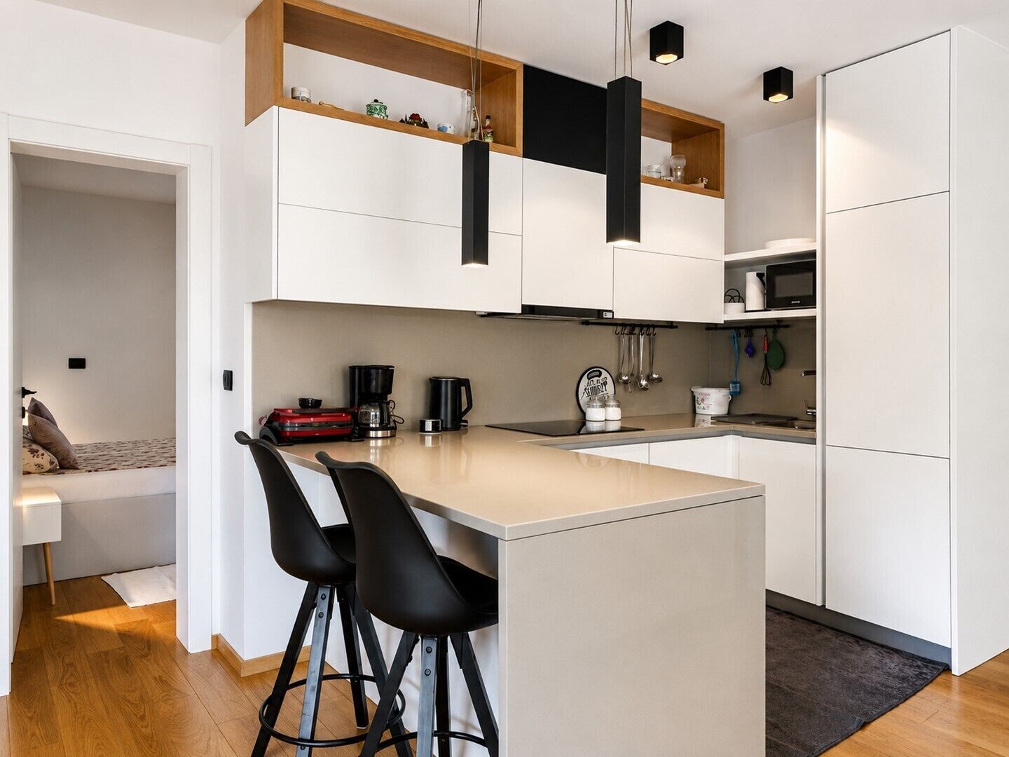 Een moderne keuken met witte kasten, een centraal eiland met barkrukken, en een magnetron.