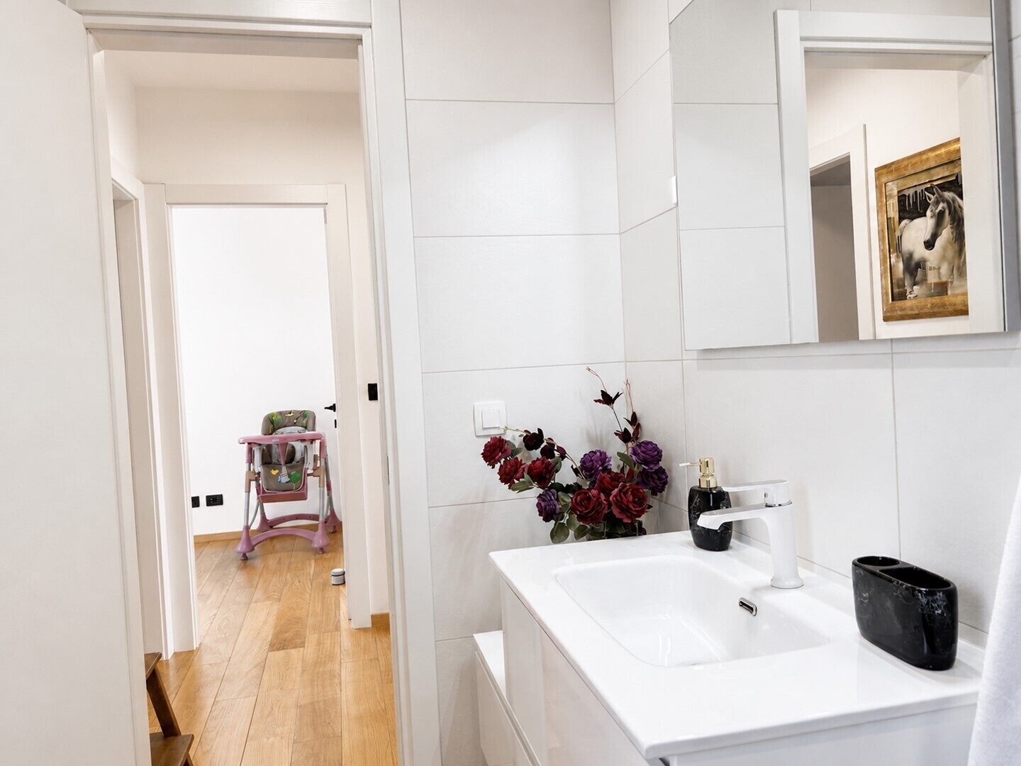 A bathroom with a white sink, a mirror, and a framed picture on the wall.