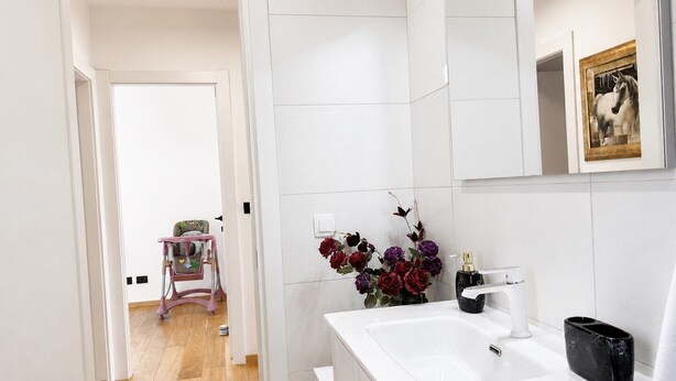 Ein Badezimmer mit einem weißen Waschbecken, einem Spiegel und einem gerahmten Bild an der Wand.