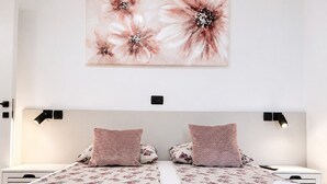 Ein Doppelzimmer mit zwei Betten, jeweils mit Blumendekoration, zwei Nachttischen und zwei Wandlampen.