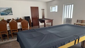 A room with a foosball table, a dining area with chairs and a table, and a bed with a blue mattress. - Vivenda Ribeiro: House with Mountain View, Private Pool and Wi-Fi (Curvos)