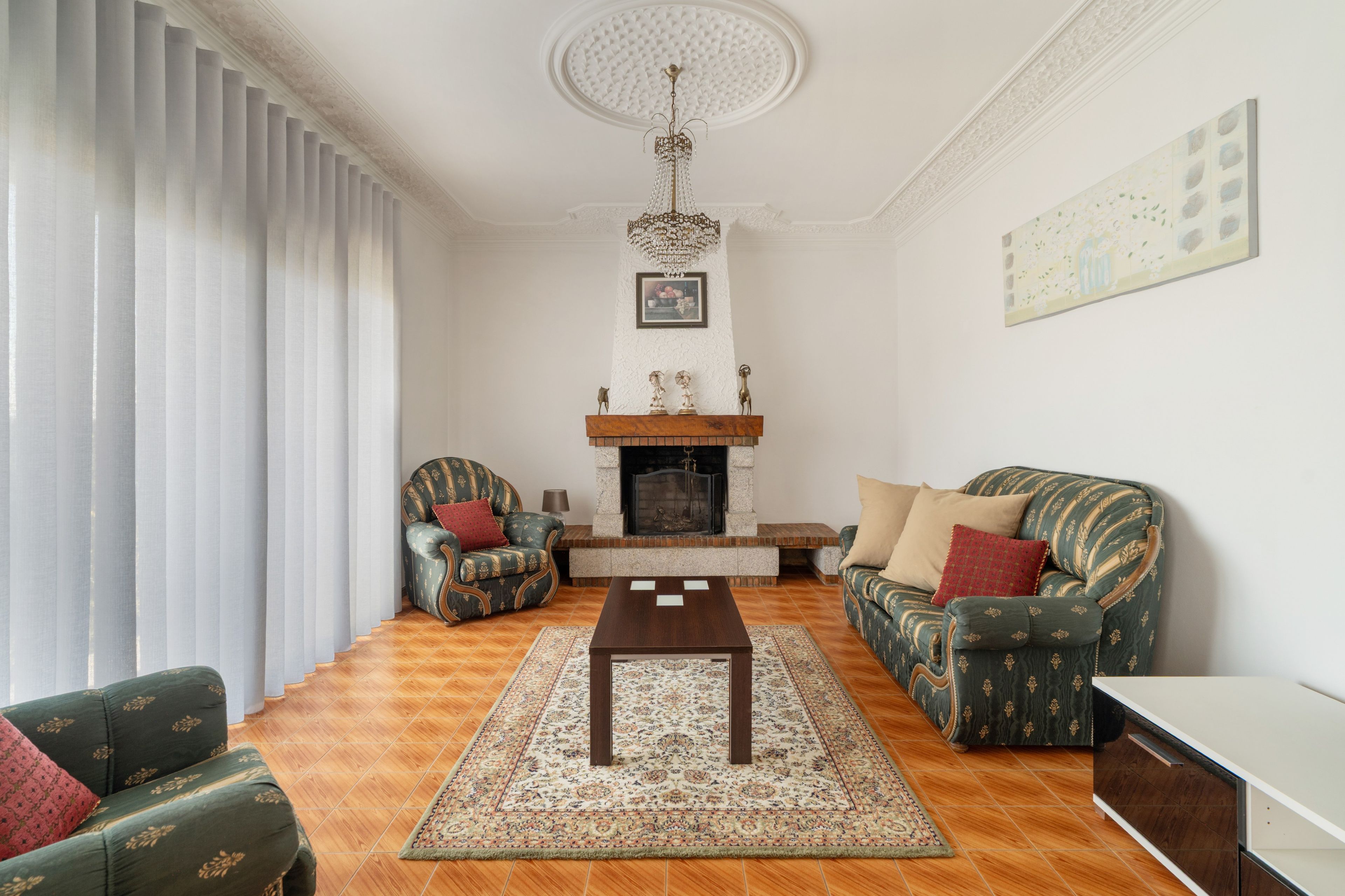 A living room with a fireplace, two sofas, a coffee table, and a patterned rug.