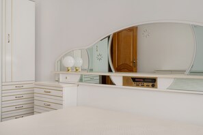 A bedroom with a bed, a dresser with drawers, a vanity with a mirror, and a radio. - Vivenda Ribeiro: House with Mountain View, Private Pool and Wi-Fi (Curvos)