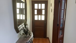 A hallway with a wooden door, a mirror, and a tiled floor. - Vivenda Ribeiro: House with Mountain View, Private Pool and Wi-Fi (Curvos)