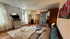 Un dormitorio con cama, televisión, armario y un cuadro en la pared.