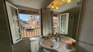 Un baño con un ventanal grande, un lavabo y un espejo.
