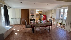 Comedor con mesa lista para cuatro, cocina al fondo y ventana con vistas.