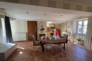 A dining area with a table set for four, a kitchen in the background, and a window with a view. - A Bright and Cozy Apartment With Stunning Views in the Heart of Lucca (Lucca)