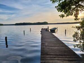 A wooden dock extending into calm water with a boat docked at the end.