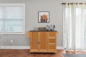 A wooden cabinet with a coffee sign, a framed picture of a bull, and a coffee maker on top.