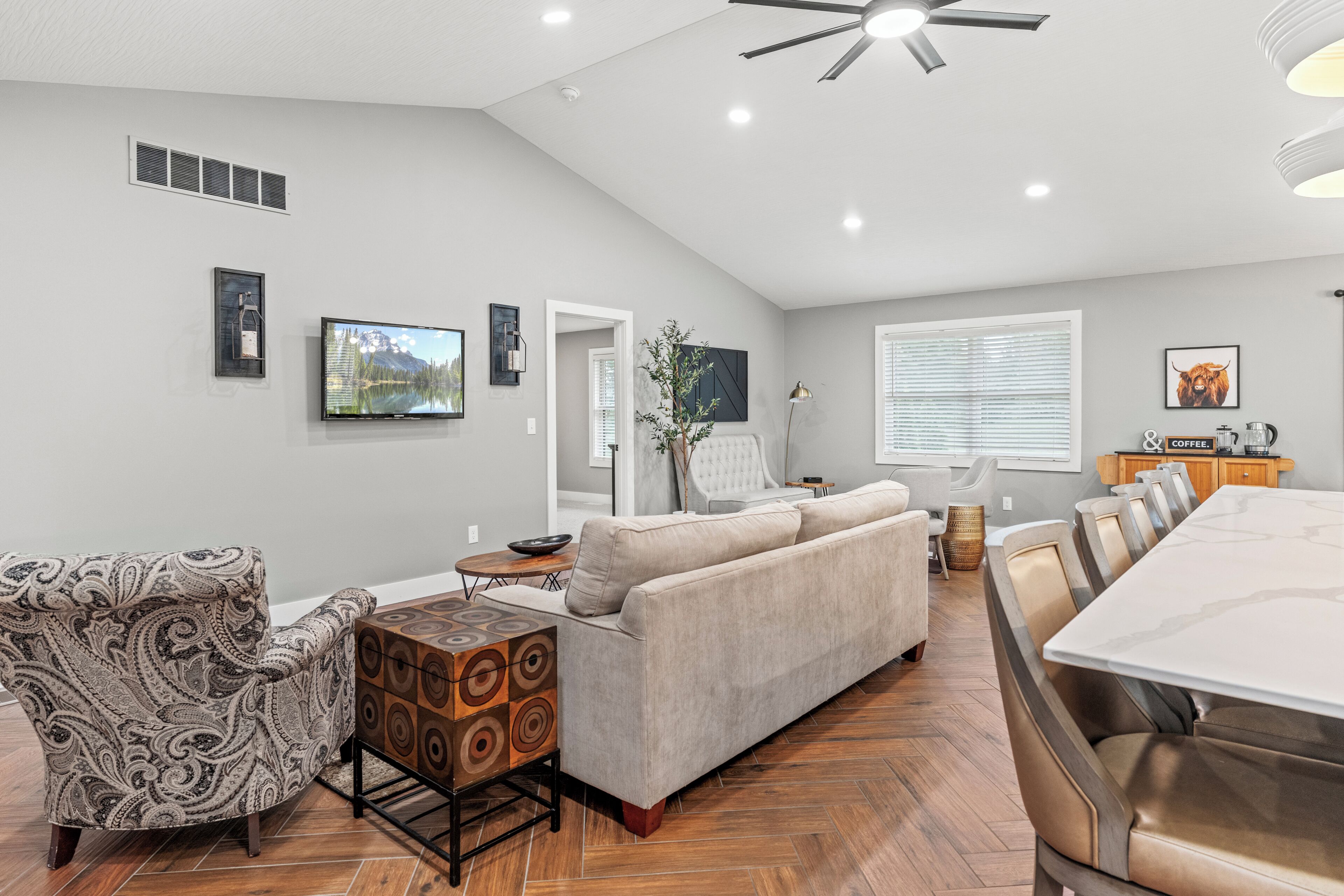A modern living room with a sofa, a patterned armchair, a coffee table, and a dining area with a table and chairs.