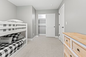 A bedroom with a bunk bed, a dresser, and a closet.