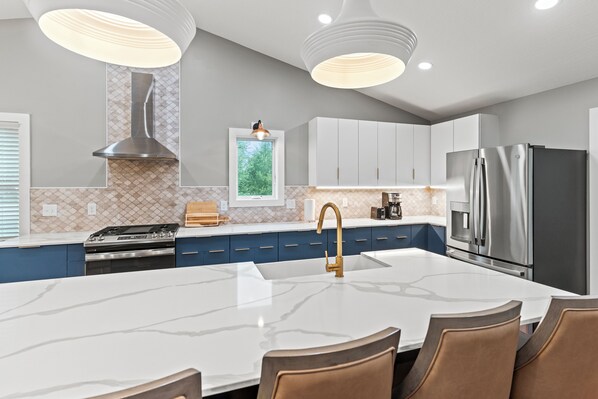 A modern kitchen with a central island, stainless steel appliances, and pendant lighting.