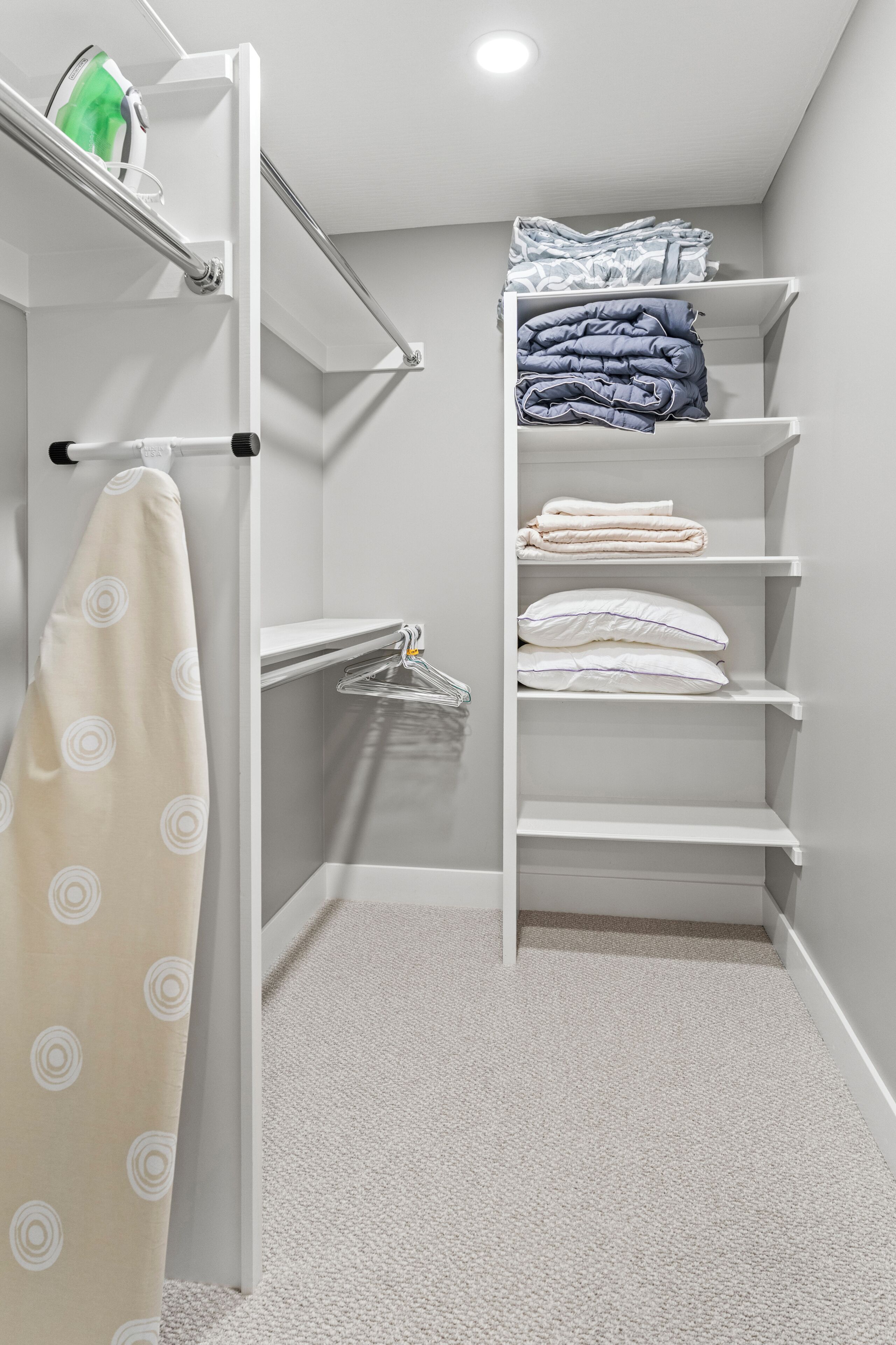 A walk-in closet with shelves for folded clothes, a hanging rack, and a towel rack.