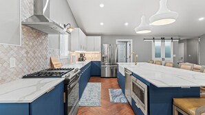 Una cocina moderna con una isla central, electrodomésticos de acero inoxidable y armarios azules.