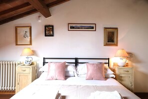 A bedroom with a bed, two bedside tables, a radiator, and wall-mounted artwork. - Wine Apartments Florence Soave (Firenze)