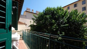 A balcony with a metal railing, a white chair, and a green door. - Wine Apartments Florence Soave (Firenze)