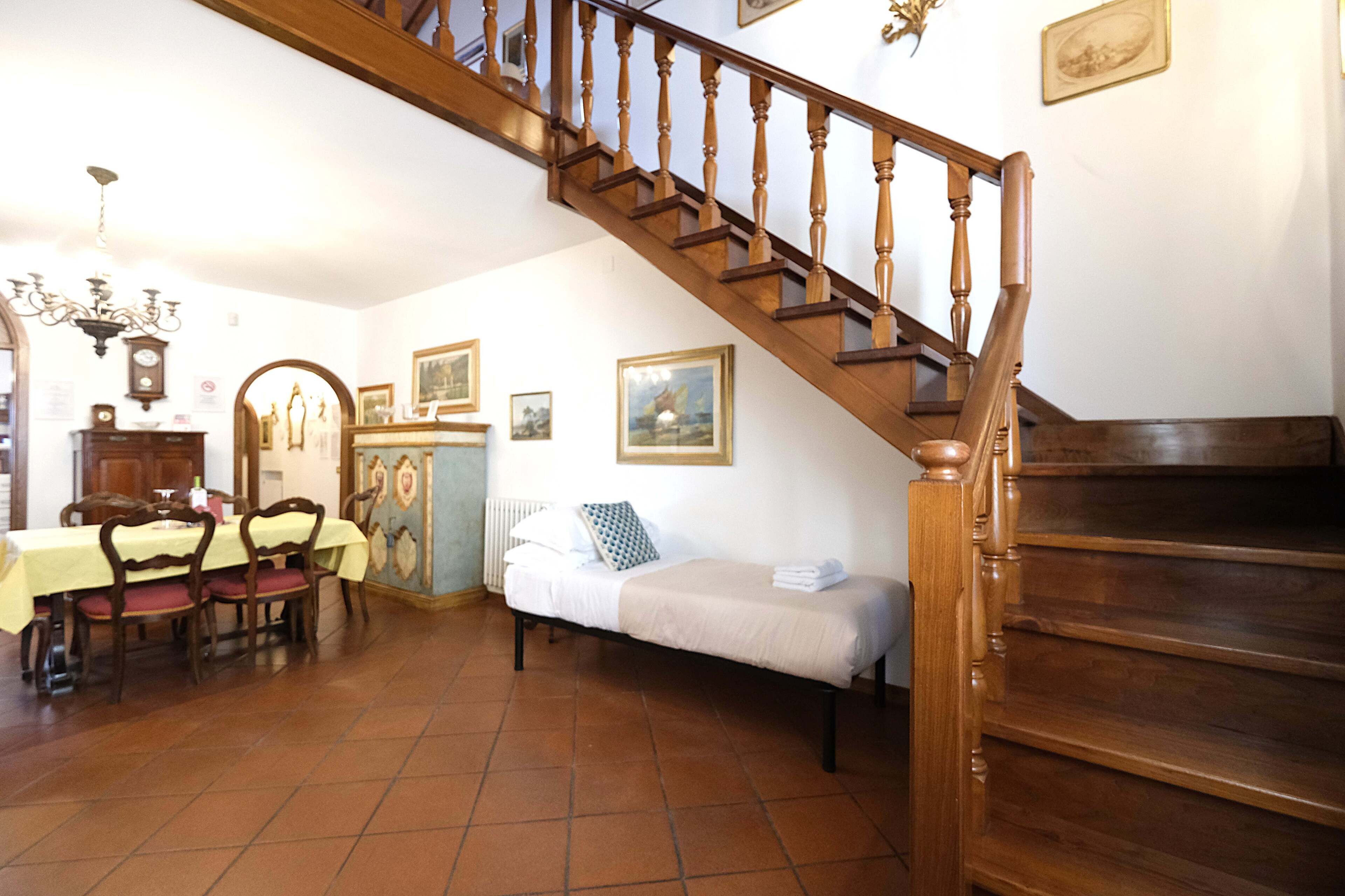 A dining area with a table and chairs, a bed with a pillow, a staircase, and a radiator.