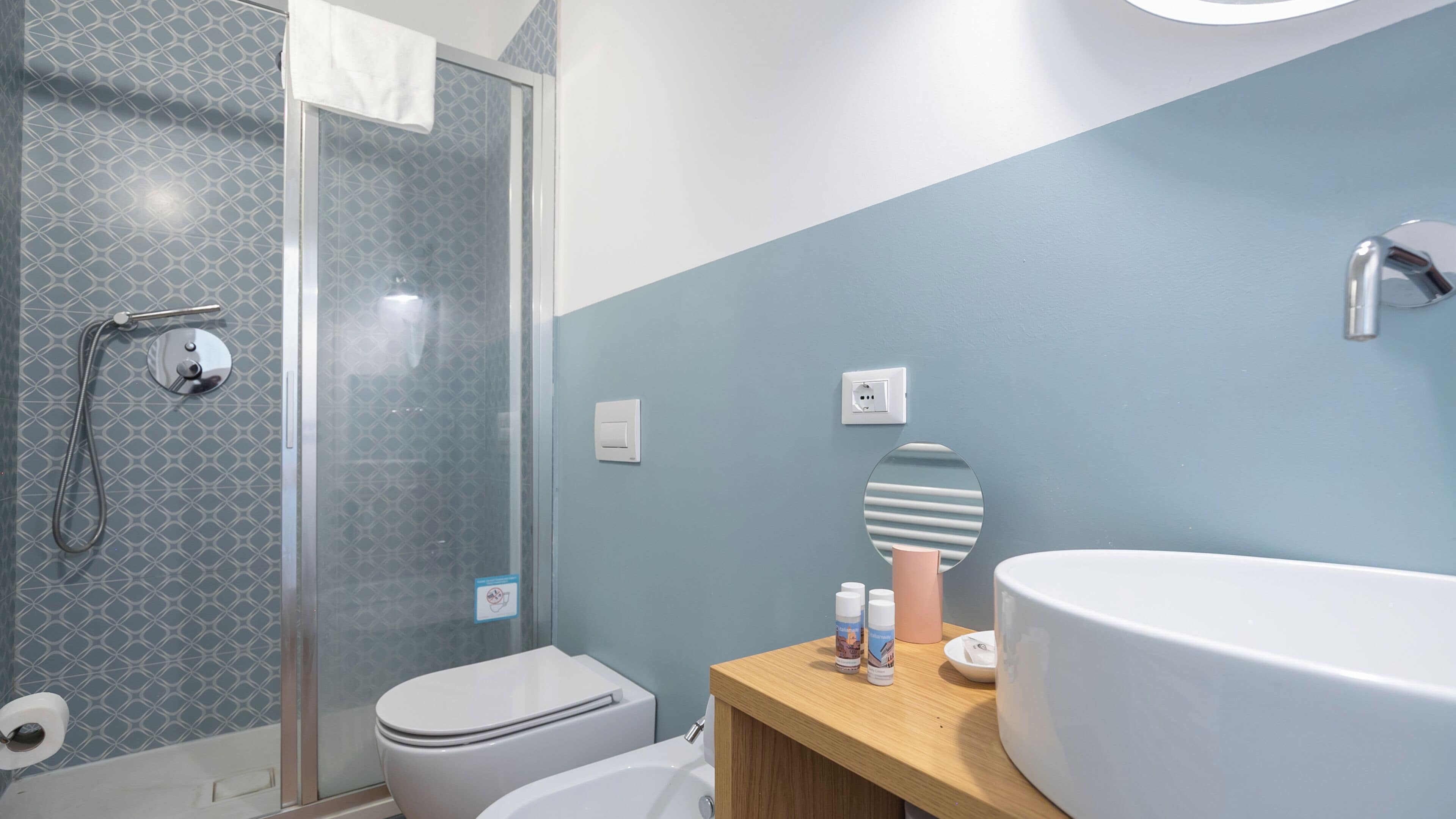 A bathroom with a shower, toilet, sink, and a mirror.