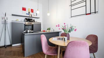 Una cucina moderna con isola centrale, un'area pranzo con sedie rosa e un vaso con fiori sul tavolo.