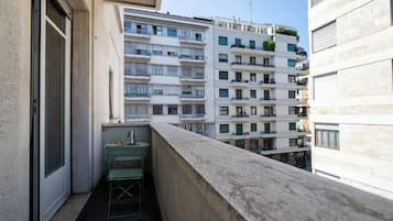 Un balcone con una sedia in metallo, un tavolino e un'astaio.
