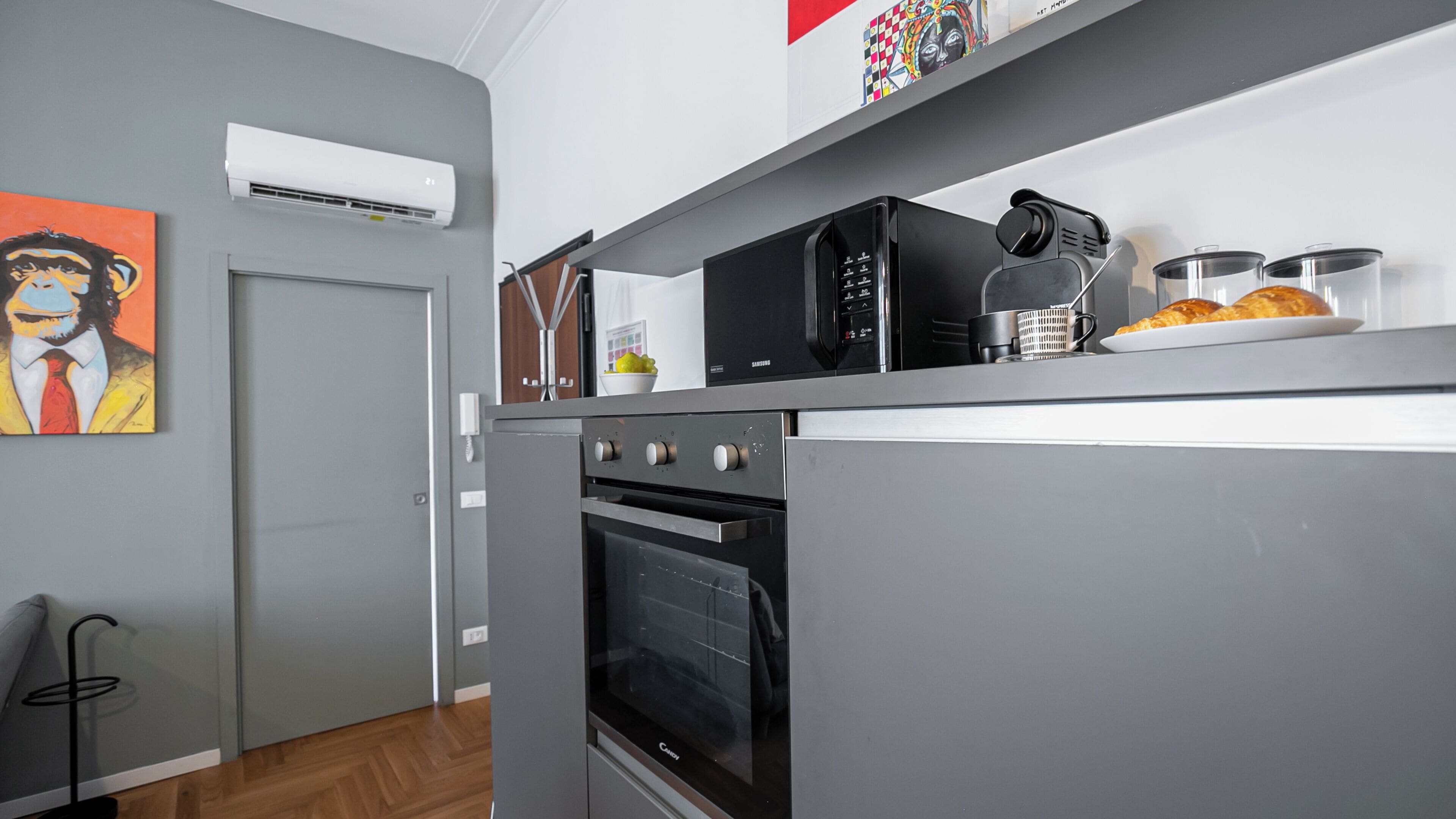 Een keuken met een inbouwoven, een magnetron en een koffieapparaat op het aanrecht.