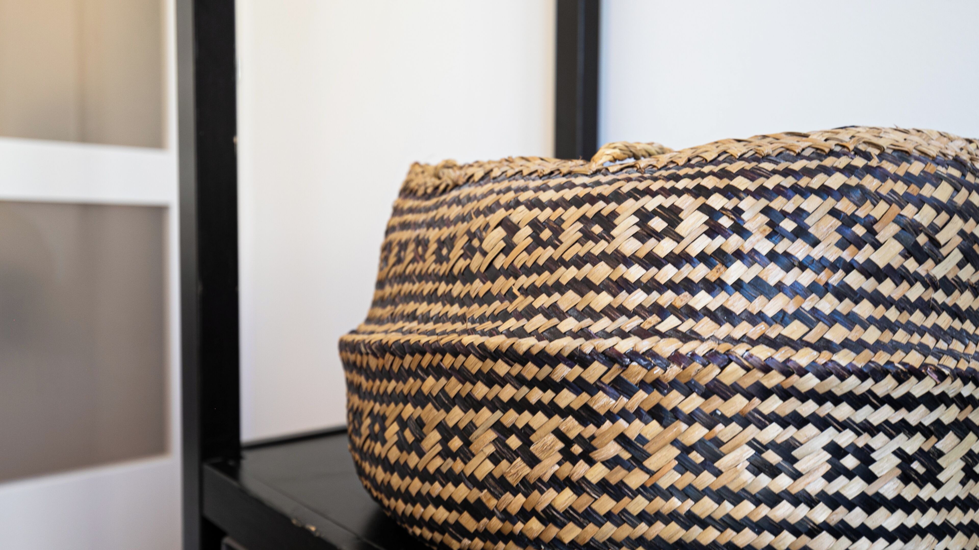 Un panier tressé orné d’un motif géométrique, posé sur une surface noire.