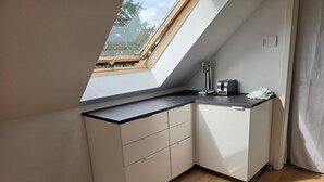 Een compacte keuken met dakraam, een inbouwtoaster en een klein aanrecht.