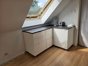 Eine kompakte Küche mit Dachfenster, integriertem Toaster und kleiner Arbeitsfläche.