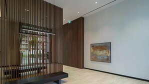 Un interior moderno con un separador de listones de madera, un banco y un cuadro abstracto en la pared.