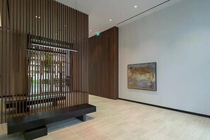 Ein modernes Interieur mit einer Holztrennwand, einer Bank und einem einzelnen, abstrakten Gemälde an der Wand.