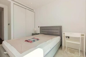 A bedroom with a bed, a bedside table, a lamp, a wardrobe, and a desk. - Apartment Sleeps 4 - Parking & Wifi (London)